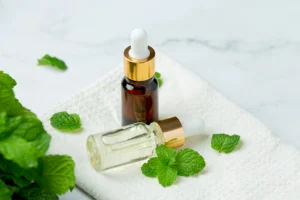 Essential oil bottle with fresh mint leaves on towel.